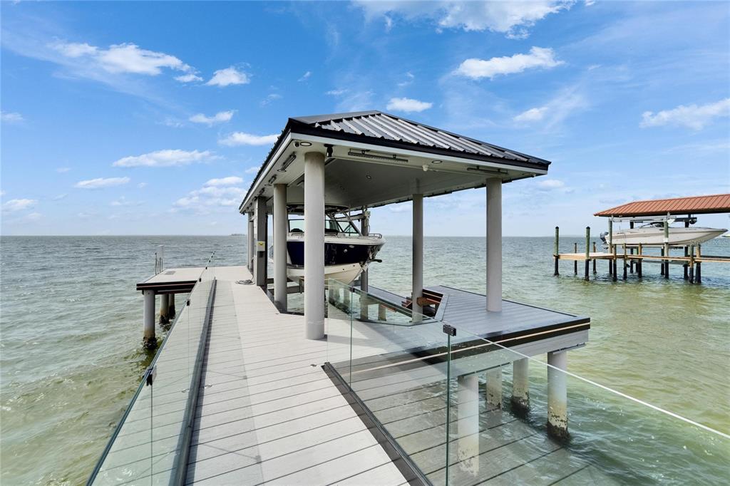 A boat lift with a metal roof sits at the end of a wooden dock — 6526 SURFSIDE BOULEVARD, APOLLO BEACH, FL