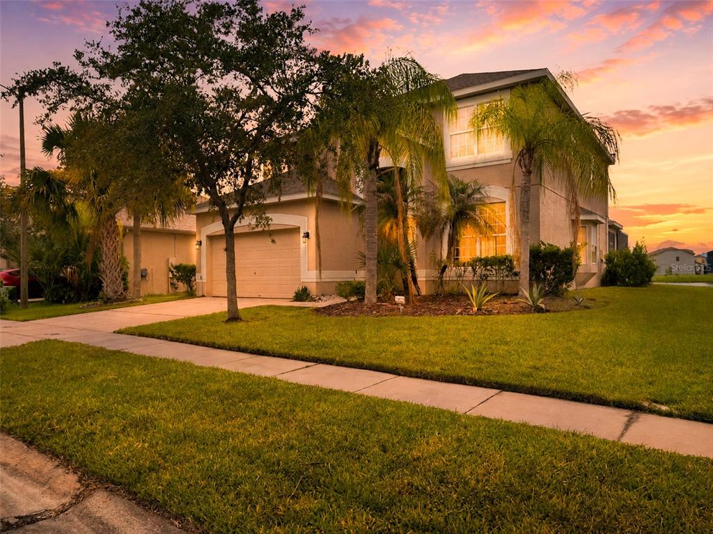 A two-story suburban house with a garage, palm trees, and a lawn at sunset — 2803 BOATING BOULEVARD, KISSIMMEE, FL