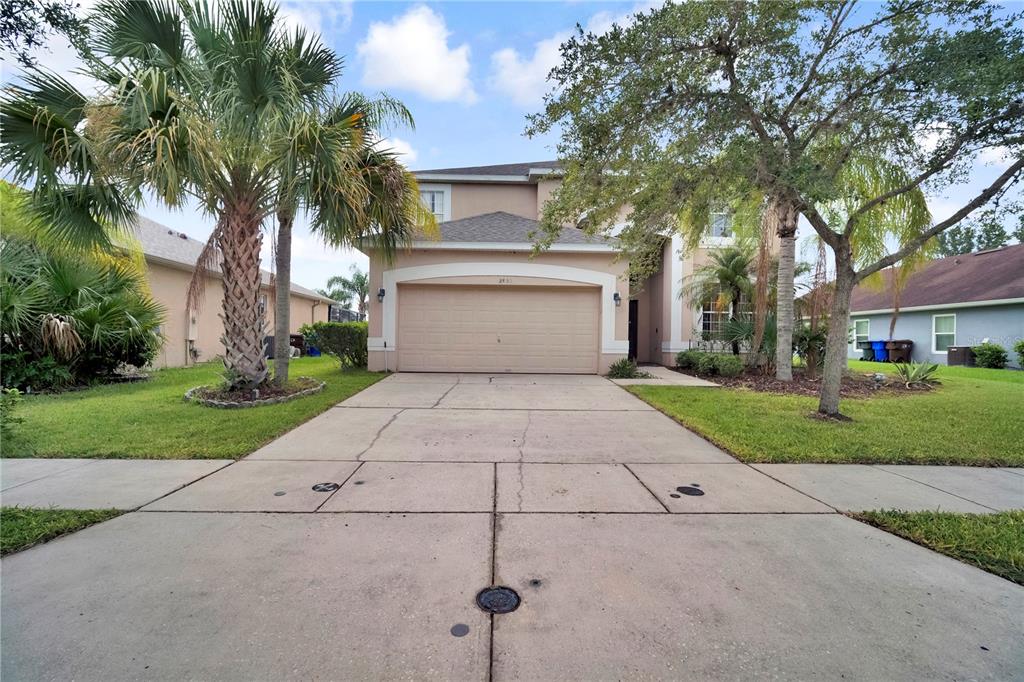 A two-story suburban house with a beige exterior, a two-car garage, and a concrete driveway — 2803 BOATING BOULEVARD, KISSIMMEE, FL