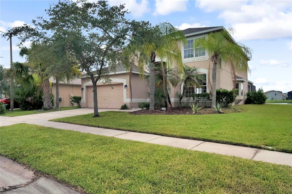 A two-story suburban house with a tan stucco exterior, a two-car garage, and palm trees — 2803 BOATING BOULEVARD, KISSIMMEE, FL