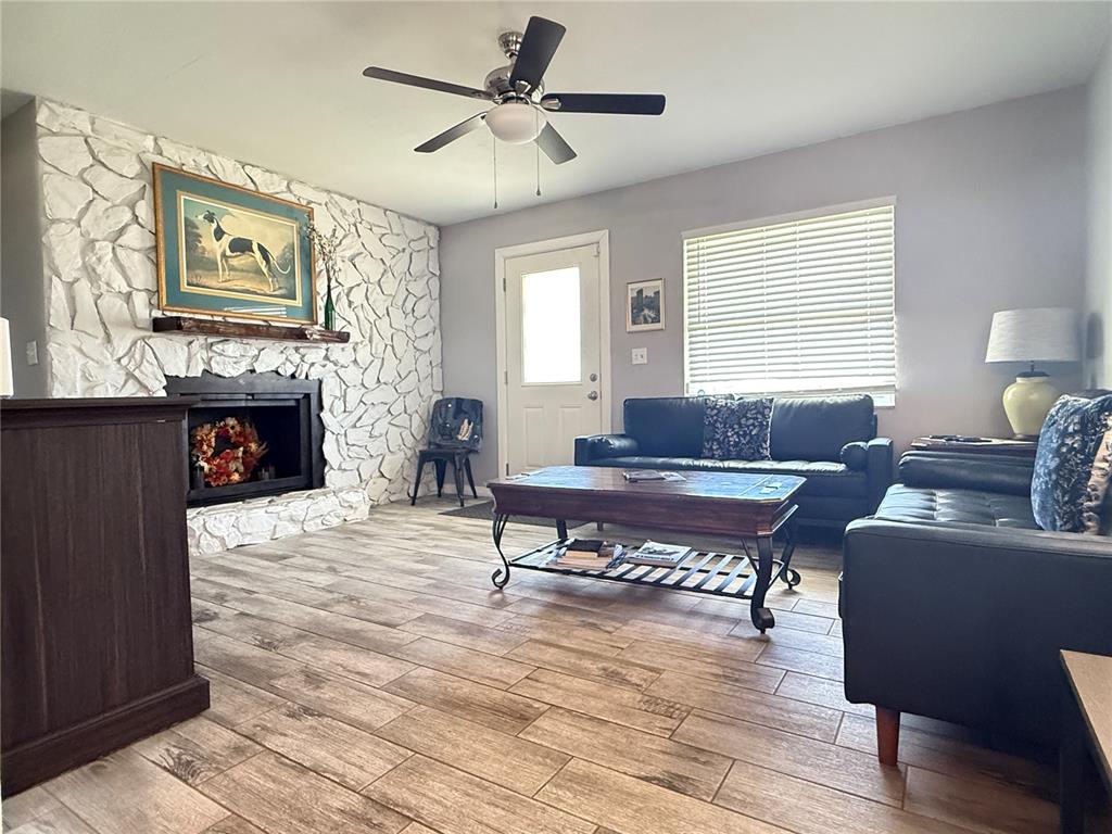 A living room features a white stone fireplace, wood-look tile flooring, and two black sofas — 6809 NW 60TH STREET, OCALA, FL
