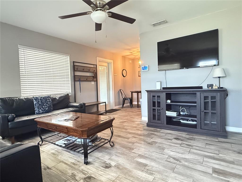 A living room features a black leather sofa, wood coffee table, and a wall-mounted television — 6809 NW 60TH STREET, OCALA, FL