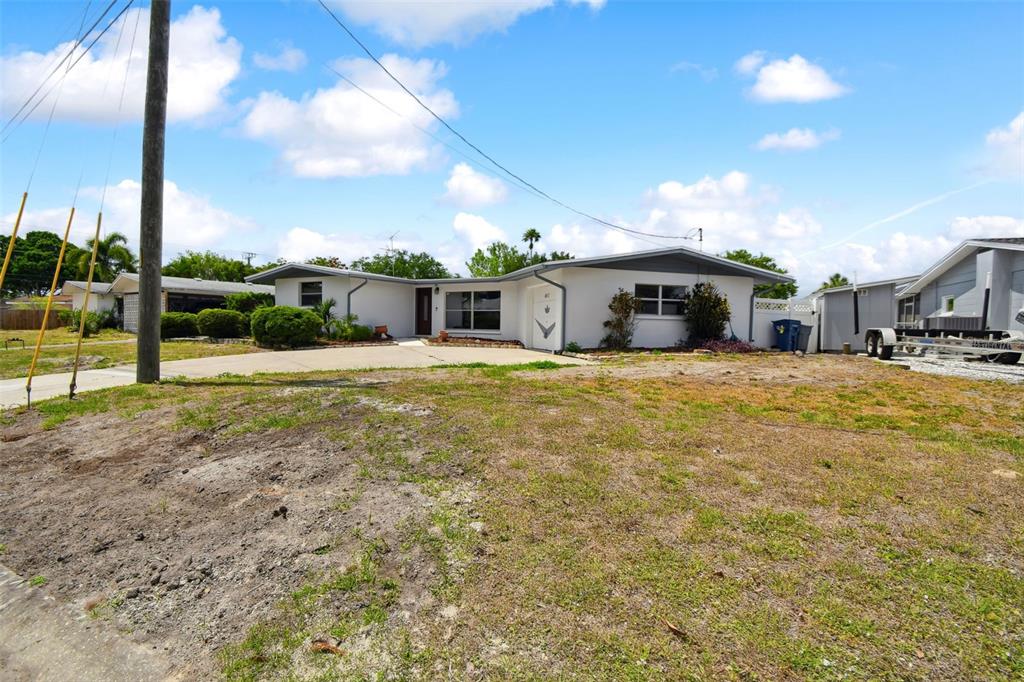 A single-story white house with a gray roof sits behind a large, sparse grassy yard — 4411 3RD AVENUE E, BRADENTON, FL