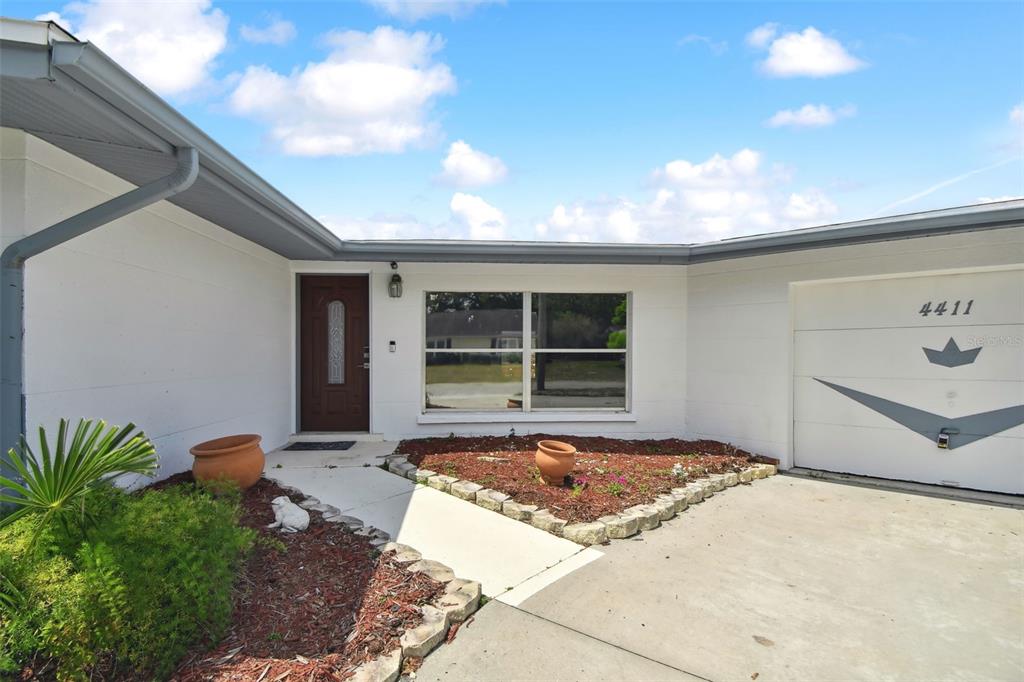 The exterior of a white house features a front door, a window, and a garage — 4411 3RD AVENUE E, BRADENTON, FL