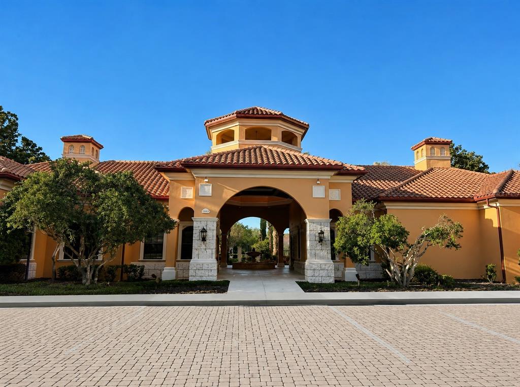 A Mediterranean-style building with a terracotta tile roof and a central arched entryway — 6169 METROWEST BOULEVARD UNIT 306, ORLANDO, FL