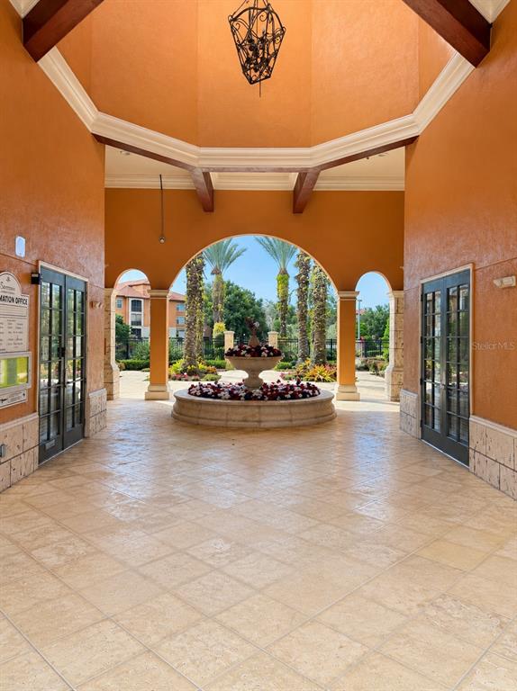 An open-air entryway features a stone-tiled floor, a central fountain, and arched openings to outdoors — 6169 METROWEST BOULEVARD UNIT 306, ORLANDO, FL
