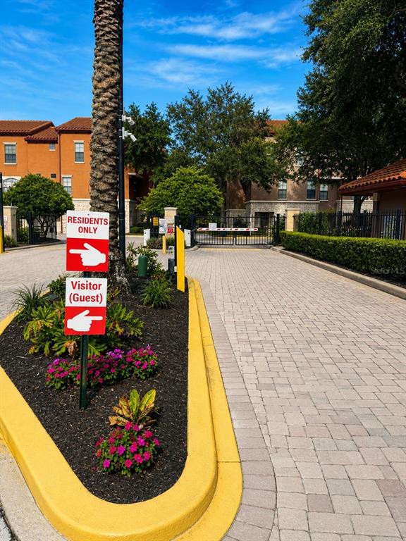 A paved entrance gate features a sign directing residents and guests to separate lanes — 6169 METROWEST BOULEVARD UNIT 306, ORLANDO, FL