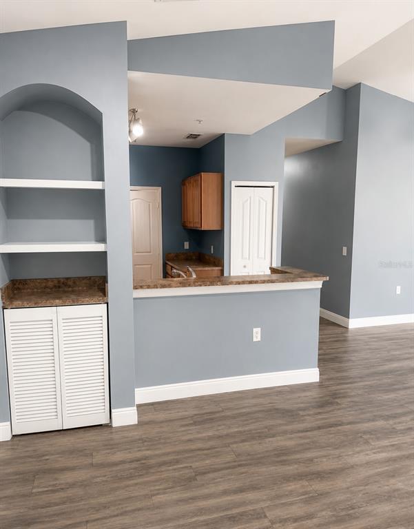A kitchen with a breakfast bar, wooden cabinets, and white shelving against blue walls — 6169 METROWEST BOULEVARD UNIT 306, ORLANDO, FL