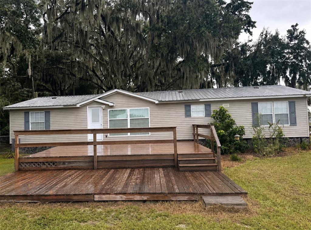 A single-story manufactured home with a large wooden deck and a metal roof — 172 E COWPEN LAKE POINT ROAD, HAWTHORNE, FL