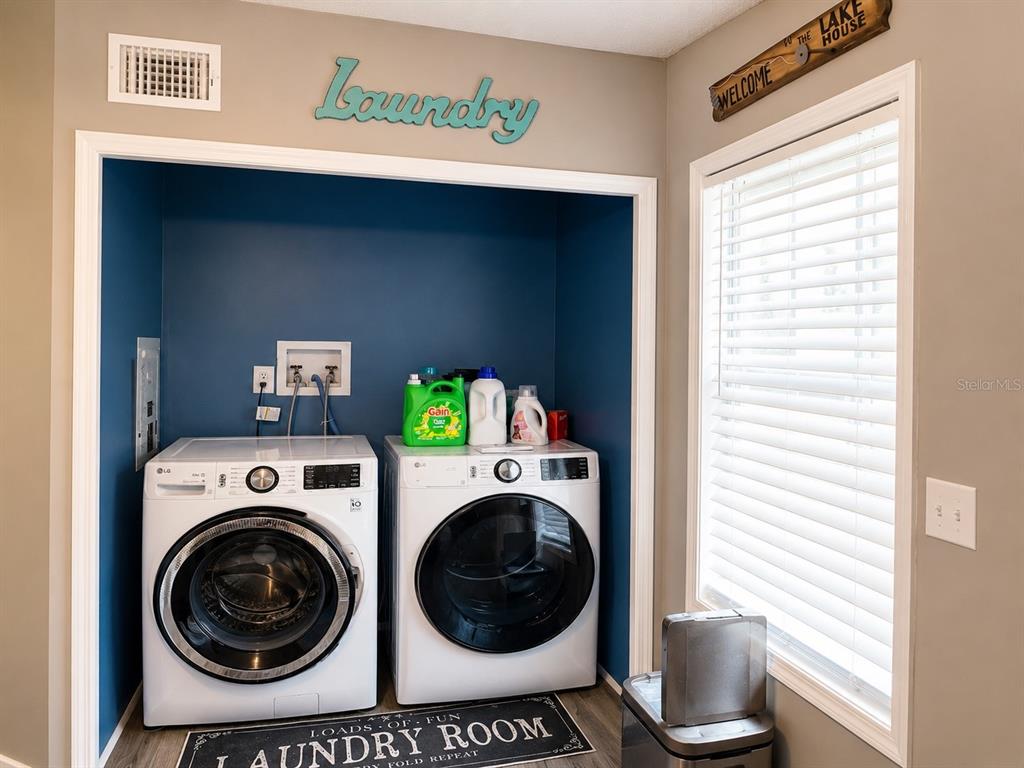 A laundry room features a front-loading washer and dryer set against a blue accent wall — 172 E COWPEN LAKE POINT ROAD, HAWTHORNE, FL