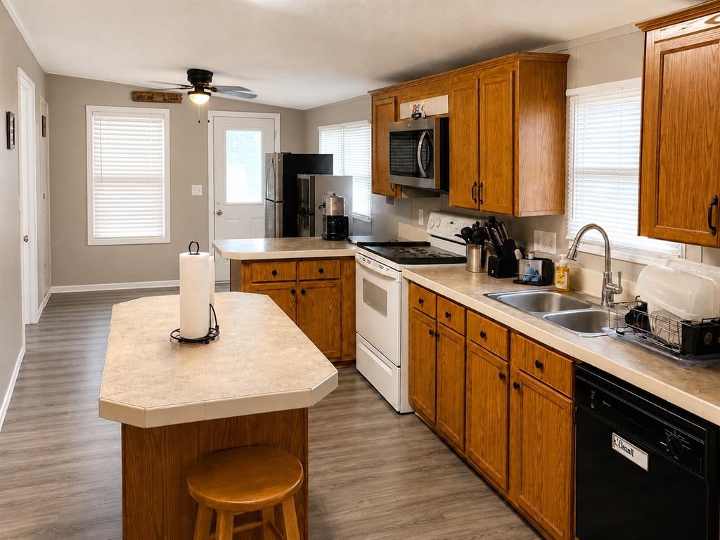 A kitchen features wood cabinets, a central island, white appliances, and light-colored countertops — 172 E COWPEN LAKE POINT ROAD, HAWTHORNE, FL