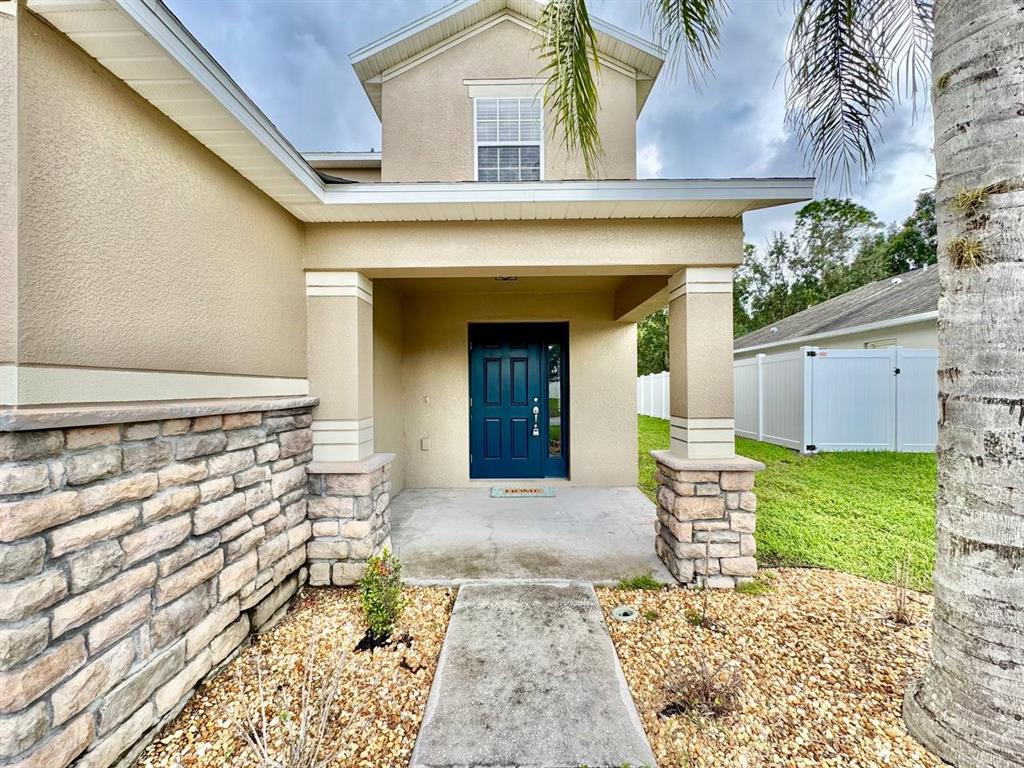 A front entryway features a blue door, stone-accented columns, and a concrete walkway — 12534 CHENWOOD AVENUE, HUDSON, FL