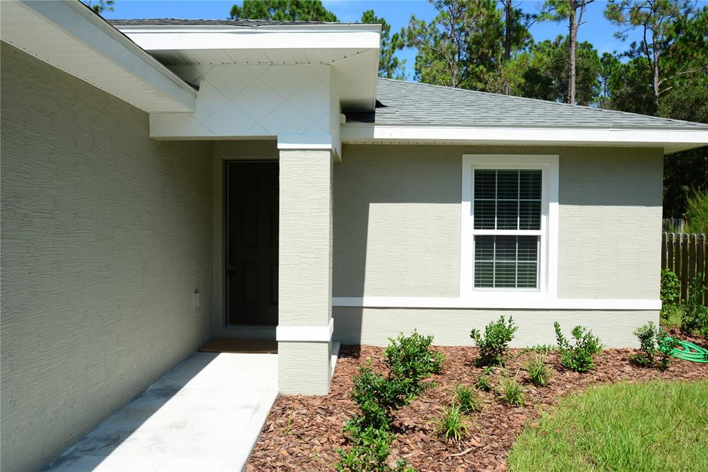 The exterior of a house features a tan stucco facade, a white-trimmed window, and an entryway — 148 SECRETARY TRAIL UNIT A/B, PALM COAST, FL