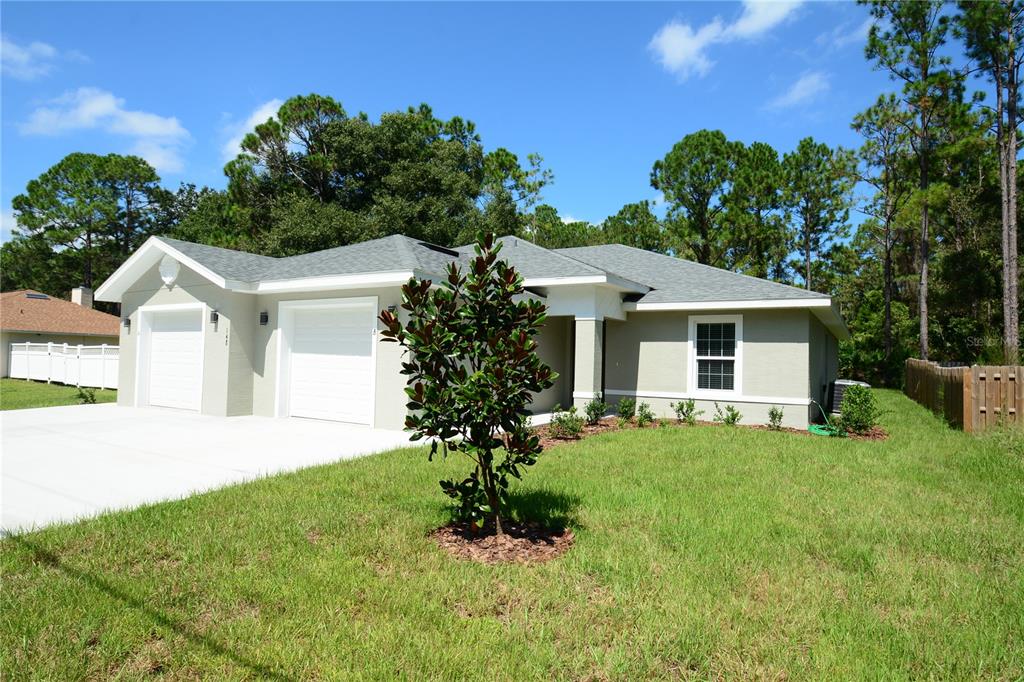 A single-story house with a two-car garage, light-colored stucco exterior, and a manicured lawn — 148 SECRETARY TRAIL UNIT A/B, PALM COAST, FL