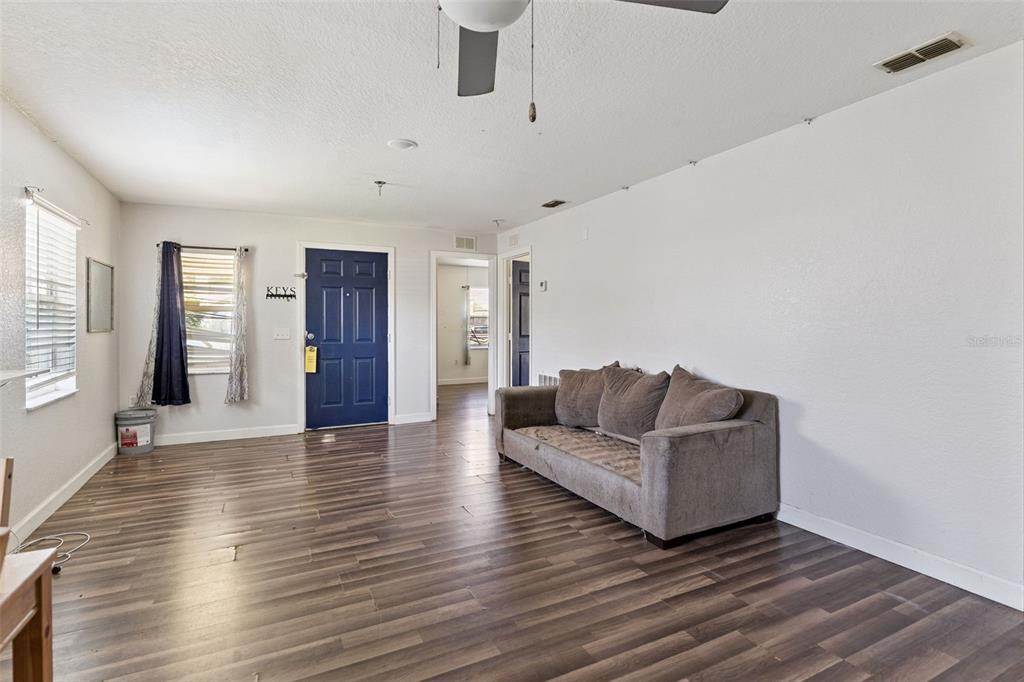A living room features wood-look flooring, a gray sofa, and a blue front door — 220 D STREET, LAKE WALES, FL