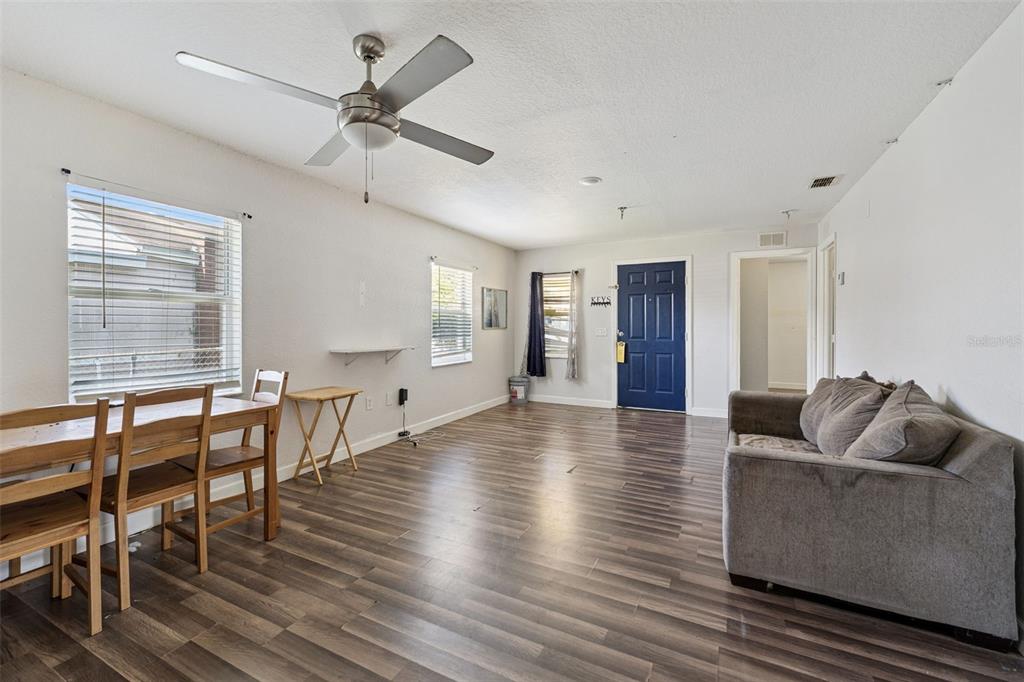 A living and dining area with wood-look flooring, a ceiling fan, and a blue front door — 220 D STREET, LAKE WALES, FL