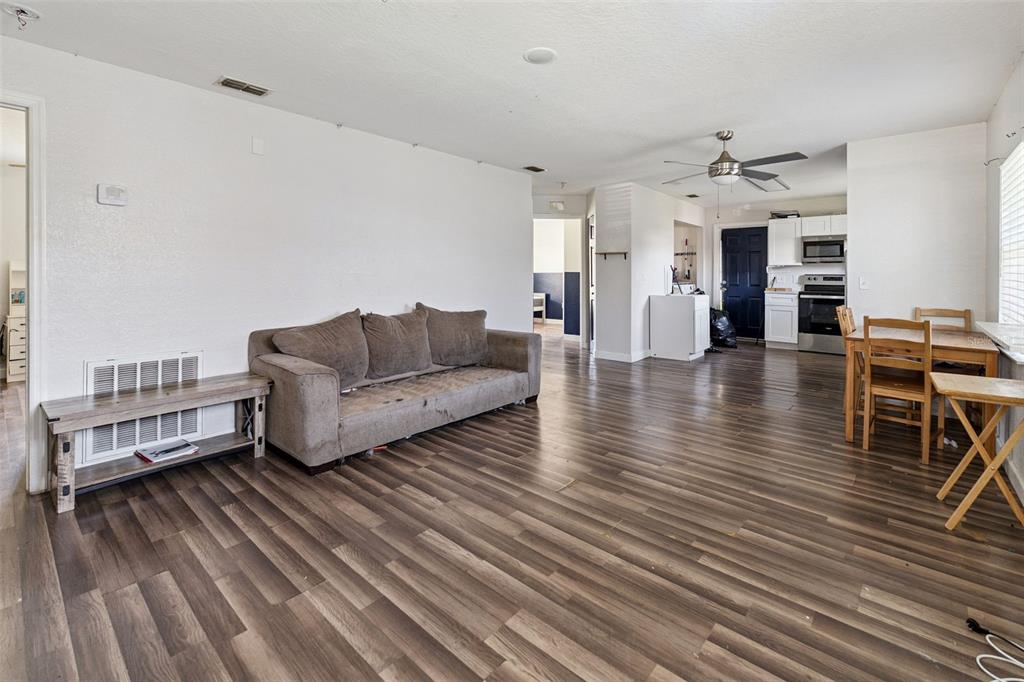 A living room and dining area with wood-look flooring, a gray sofa, and white walls — 220 D STREET, LAKE WALES, FL