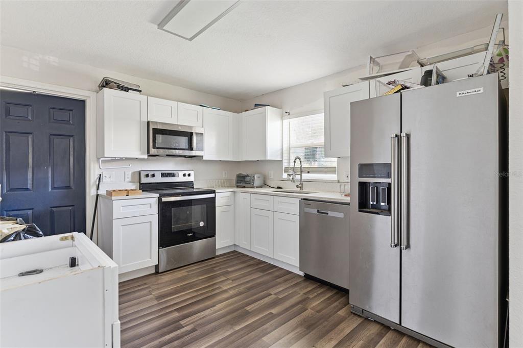 A kitchen with white cabinets, stainless steel appliances, and wood-look flooring — 220 D STREET, LAKE WALES, FL