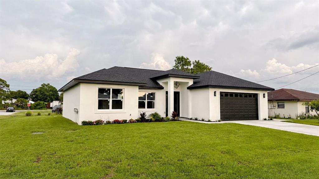 A modern, single-story house with white stucco walls, a dark roof, and a two-car garage — 4200 LEAF ROAD, SEBRING, FL