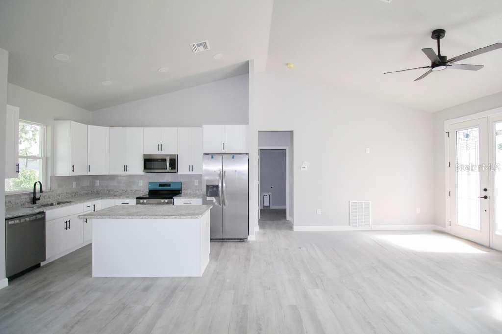 A modern kitchen with white cabinets, stainless steel appliances, and an island in an open-concept room — 4200 LEAF ROAD, SEBRING, FL