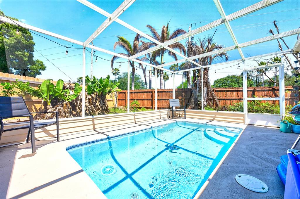 A screened-in pool enclosure with a rectangular swimming pool and a wooden privacy fence — 1599 PGA BOULEVARD, MELBOURNE, FL