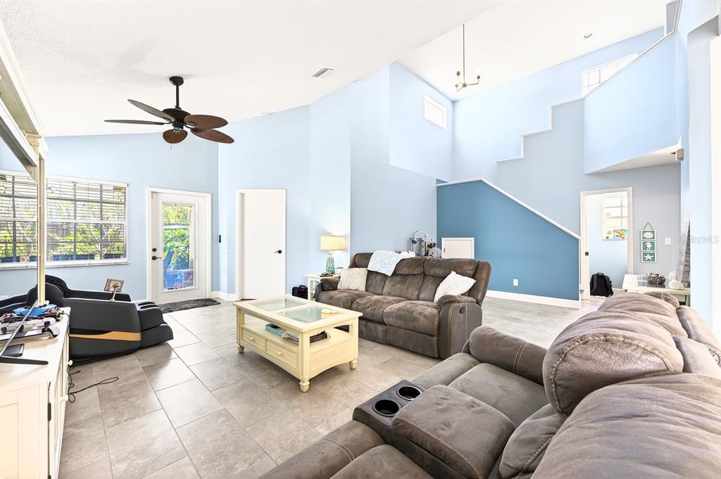 A living room features light blue walls, tile flooring, a vaulted ceiling, and two brown sofas — 1599 PGA BOULEVARD, MELBOURNE, FL
