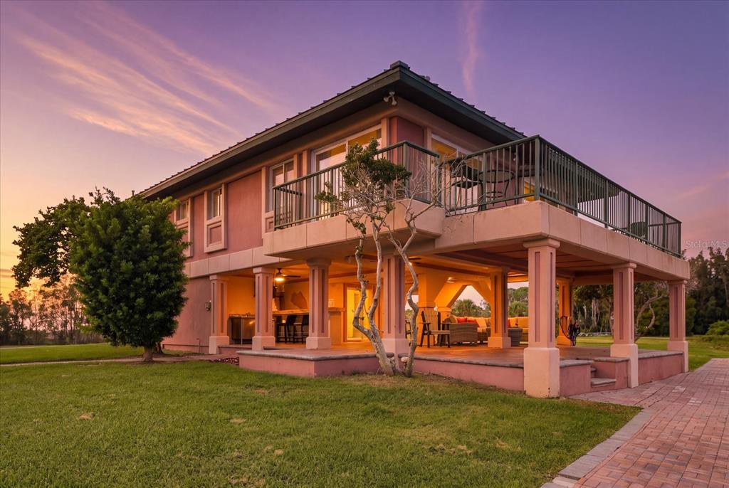 A two-story house with a raised deck and a covered patio area at sunset — 3198 INDIAN GULF LANE, HERNANDO BEACH, FL
