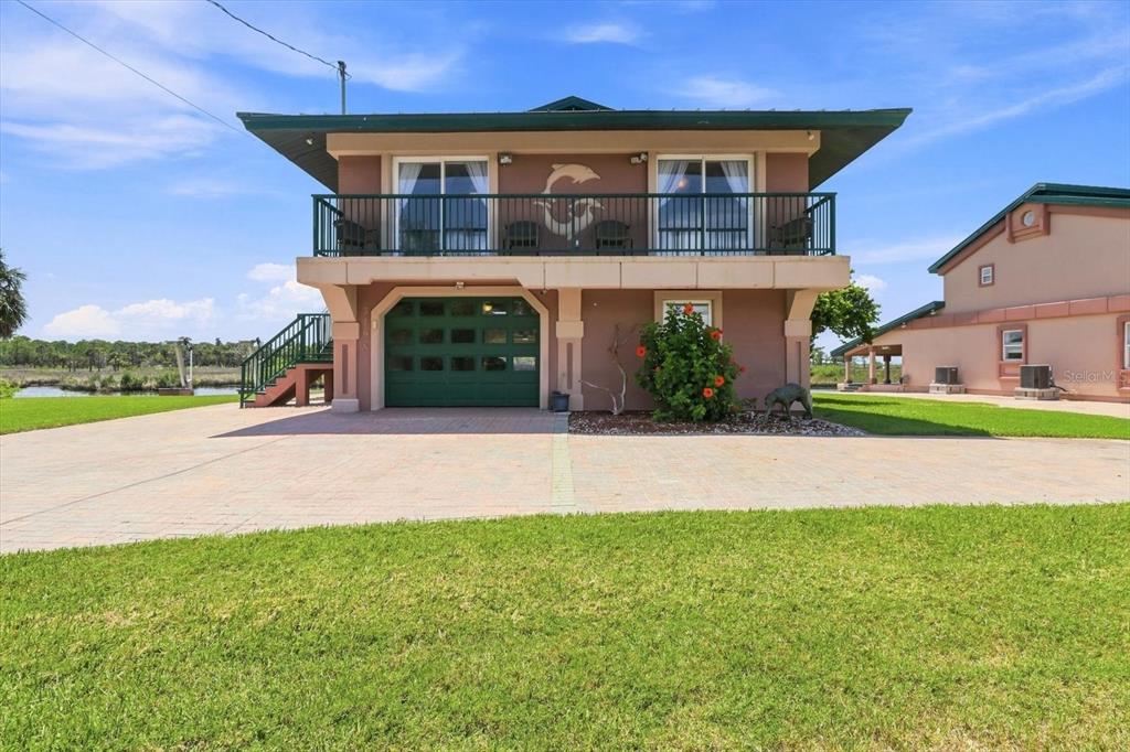 A two-story house with a green garage door, a balcony, and a paved driveway — 3198 INDIAN GULF LANE, HERNANDO BEACH, FL