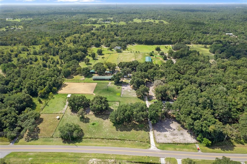 An aerial view shows a rural property with pastures, a riding arena, and several buildings — 11046 KITTEN TRAIL, HUDSON, FL