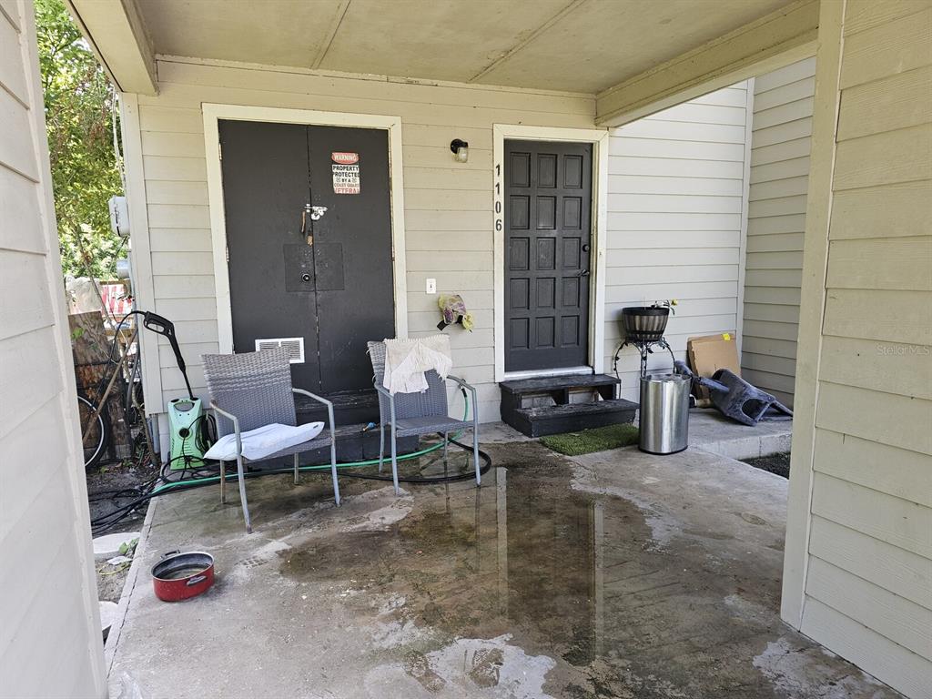 A covered concrete patio features two chairs, a storage closet, and a front door — 1106-1108 COUNTRY CLUB LANE, LAKELAND, FL