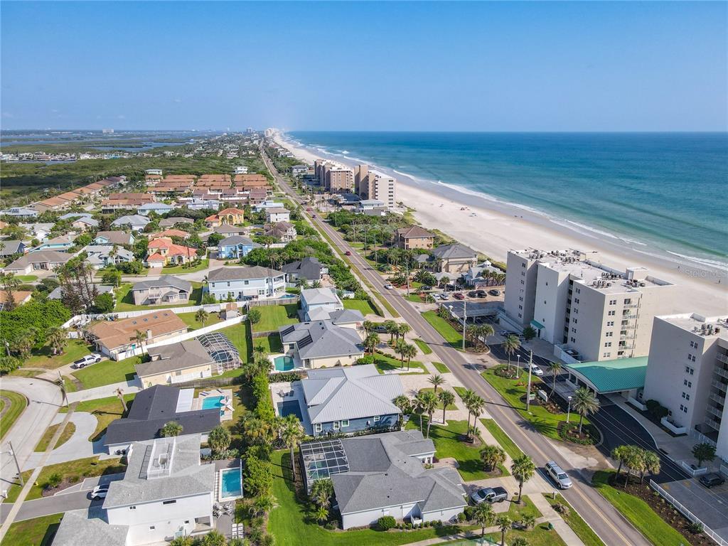 An aerial view shows a coastal neighborhood with houses, apartment buildings, and a sandy beach — 4494 S ATLANTIC AVENUE, PONCE INLET, FL