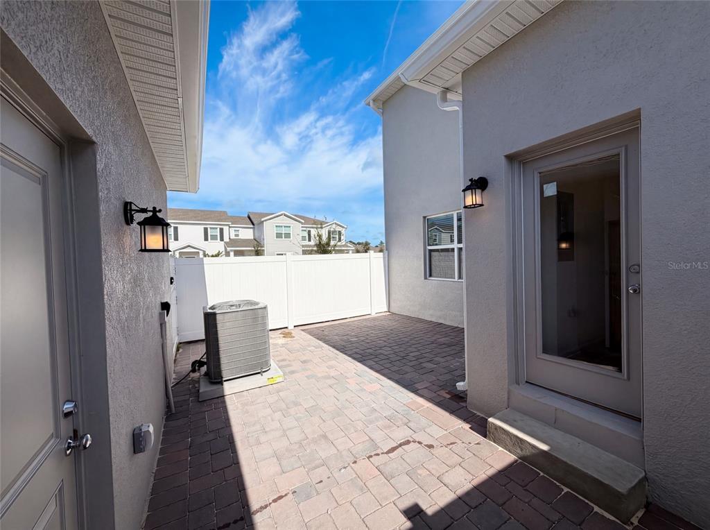 A paved patio area sits between two exterior walls with an air conditioning unit — 2172 RIDER RAIN LANE, APOPKA, FL