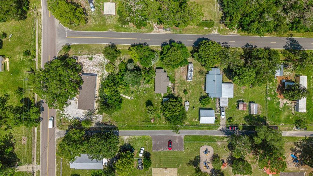 An aerial view shows several houses and outbuildings situated on a large, tree-filled residential lot — 10085 PLUM STREET, HAMPTON, FL