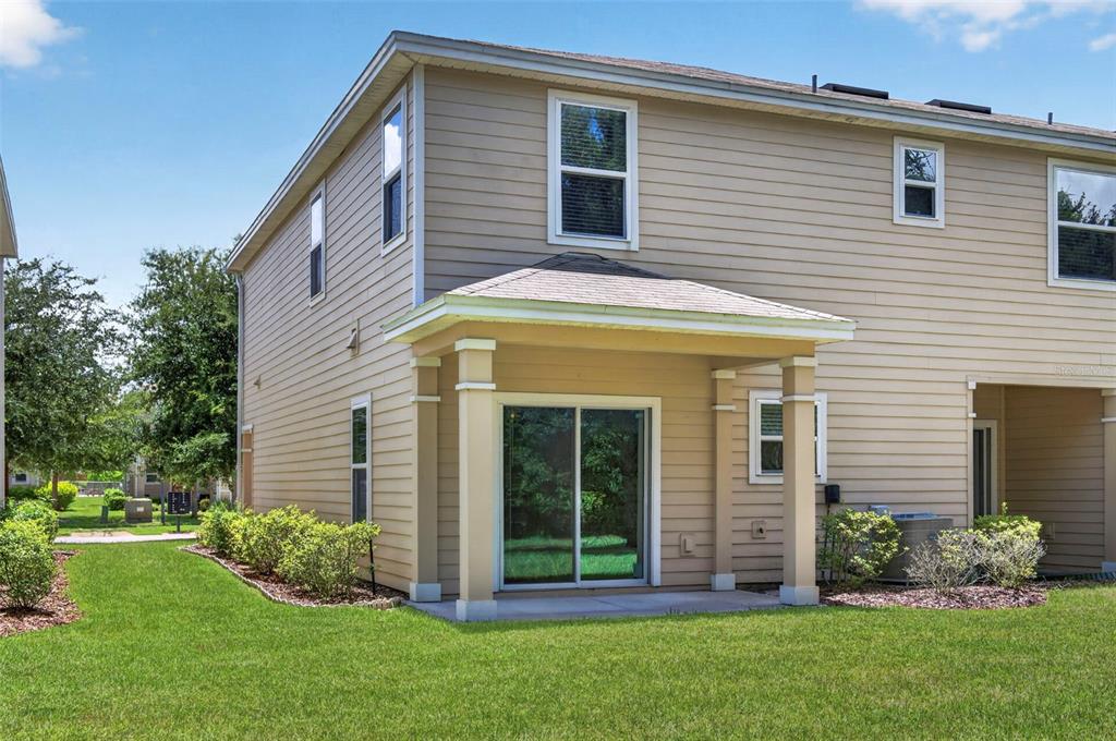 The exterior of a two-story tan house features a covered patio with sliding glass doors — 93 BELLA VITA WAY, ORMOND BEACH, FL