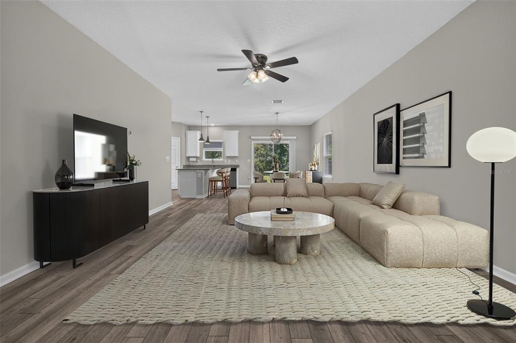 A living room with a beige sectional, round stone coffee table, and open-concept kitchen — 93 BELLA VITA WAY, ORMOND BEACH, FL