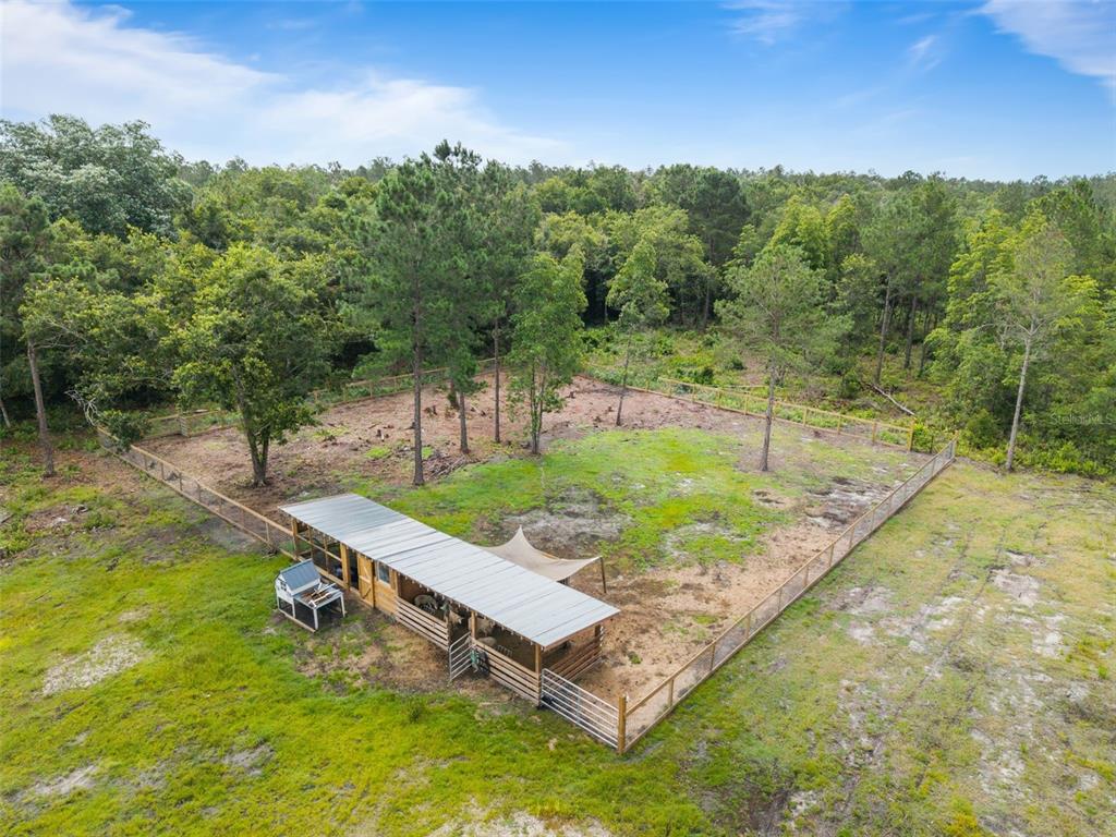 An aerial view shows a fenced animal enclosure with a shed and shade structure — 5747 RETREAT ROAD, KEYSTONE HEIGHTS, FL