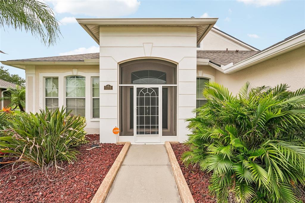 The exterior of a house features a concrete walkway leading to a screened front entrance — 5319 120TH AVENUE E, PARRISH, FL