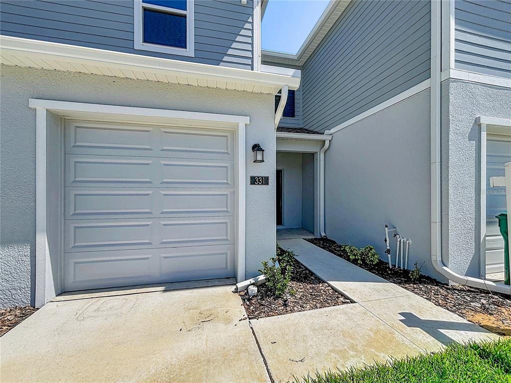 The exterior of a two-story townhouse features a single-car garage and a concrete walkway — 331 SOL VISTA DRIVE, DUNDEE, FL