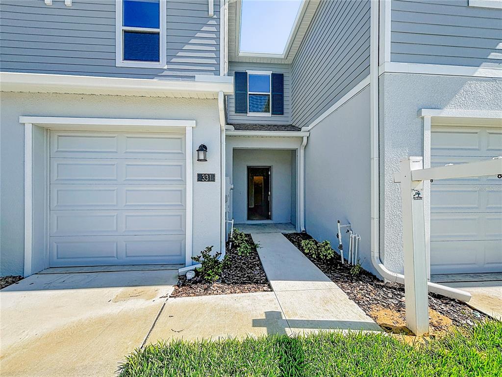 A two-story townhouse exterior features a single-car garage, a recessed entryway, and light blue siding — 331 SOL VISTA DRIVE, DUNDEE, FL