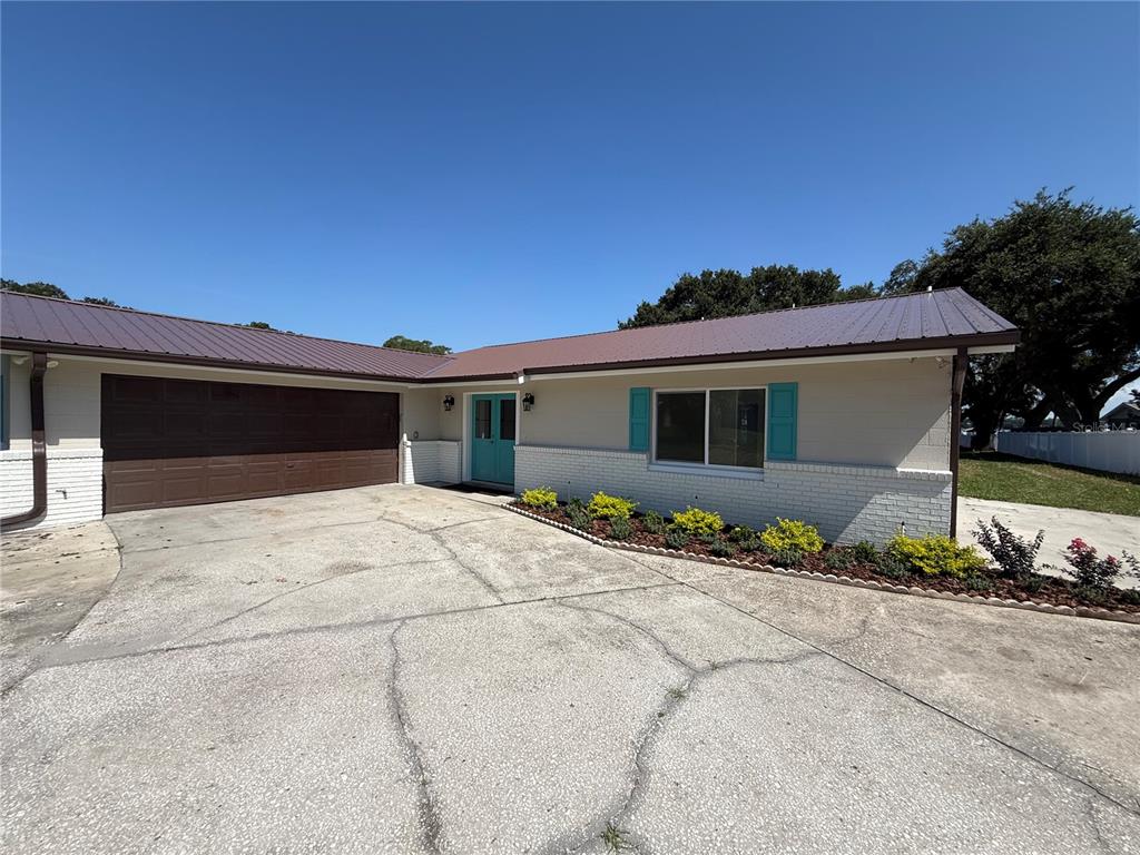 A single-story house with a brown metal roof, white brick base, and teal accents — 1225 HOFFNER AVENUE, ORLANDO, FL