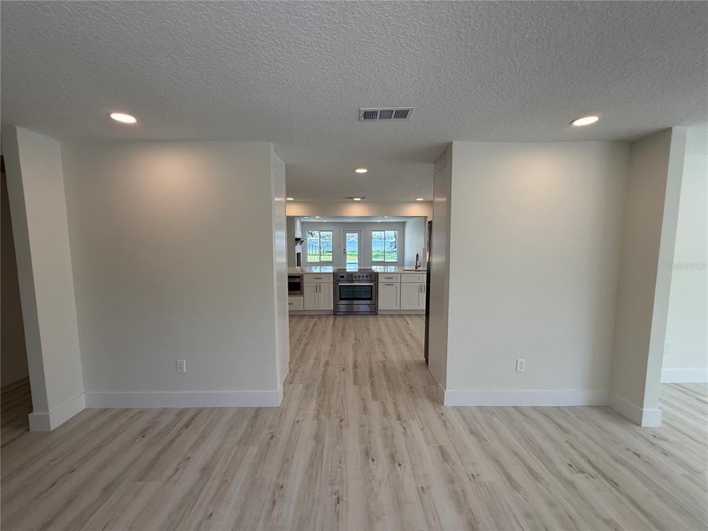 An entryway features light wood-look flooring, white trim, two closed doors, and a double front door — 1225 HOFFNER AVENUE, ORLANDO, FL