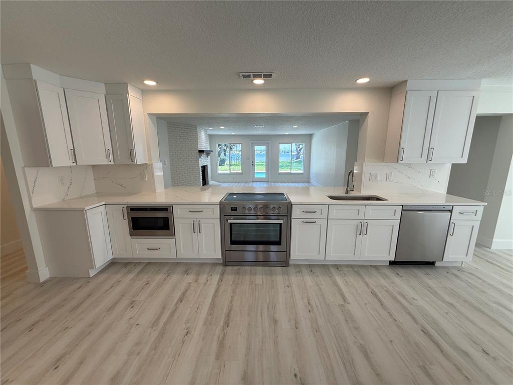 An interior view of a room with light wood-look flooring and multiple white doors — 1225 HOFFNER AVENUE, ORLANDO, FL