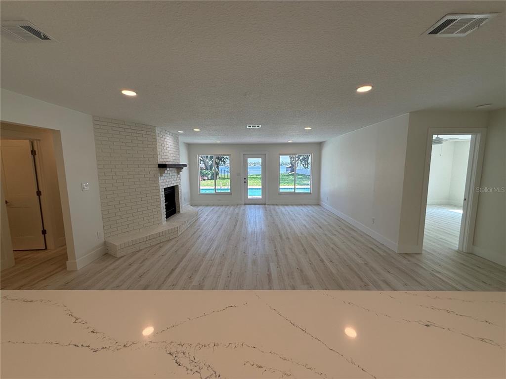 An empty room with light wood-look flooring, white walls, recessed lighting, and multiple windows — 1225 HOFFNER AVENUE, ORLANDO, FL