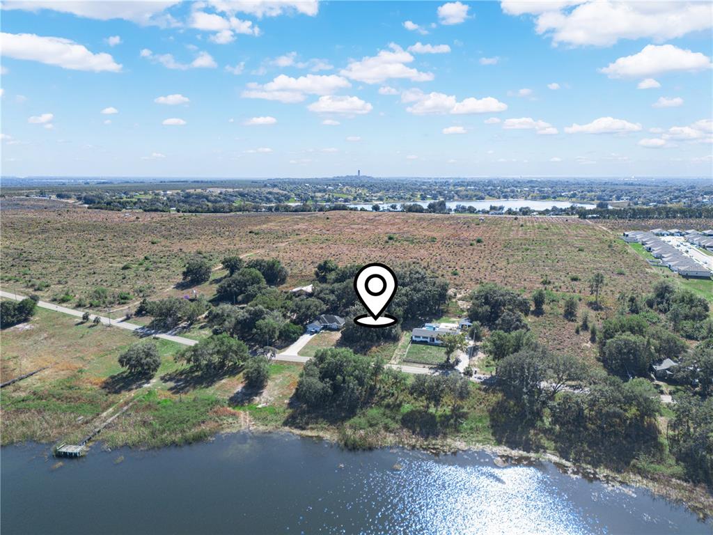 An aerial view shows a house near a lake surrounded by trees and open land — 0 LAKE MABEL LOOP RD, LAKE WALES, FL