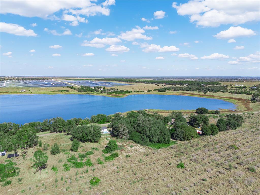 An aerial view shows a large lake surrounded by trees, fields, and a solar farm — 0 LAKE MABEL LOOP RD, LAKE WALES, FL