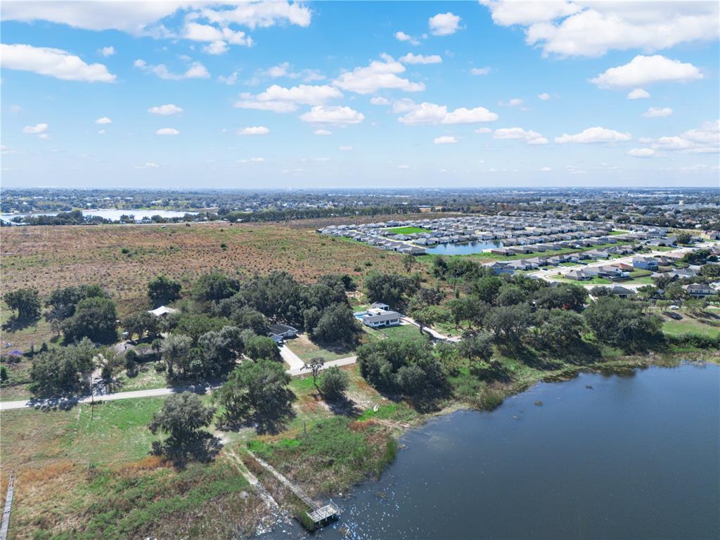 An aerial view shows a lakefront property with trees, a dock, and a nearby neighborhood — 0 LAKE MABEL LOOP RD, LAKE WALES, FL