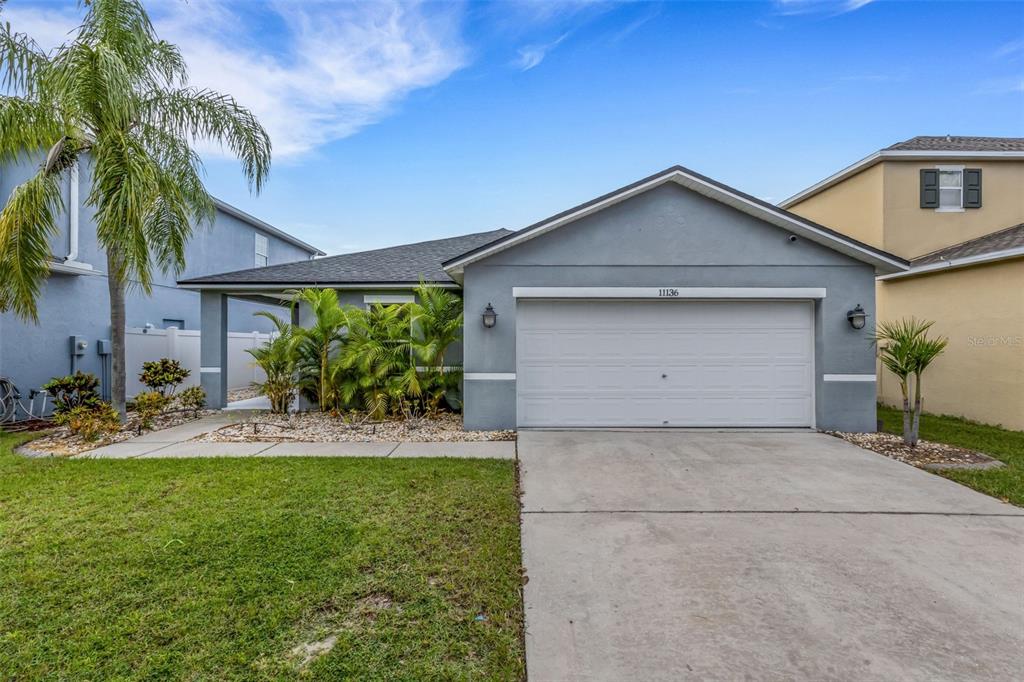 A single-story gray house with a two-car garage, a palm tree, and landscaping — 11136 GOLDEN SILENCE DRIVE, RIVERVIEW, FL
