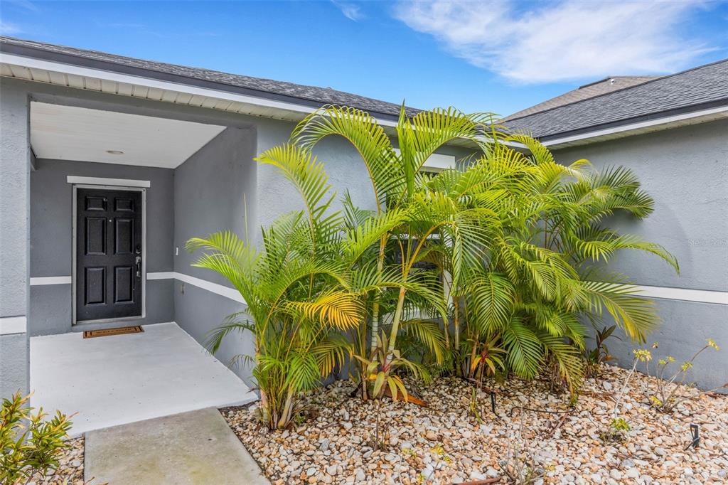 The exterior of a gray house features a covered entryway with a black front door — 11136 GOLDEN SILENCE DRIVE, RIVERVIEW, FL