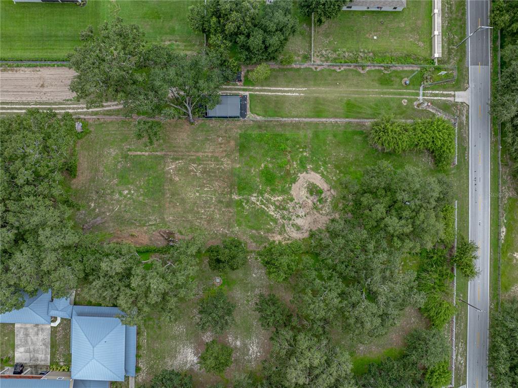 An aerial view shows a large, grassy vacant lot bordered by trees and a road — OLD BERKLEY ROAD, AUBURNDALE, FL
