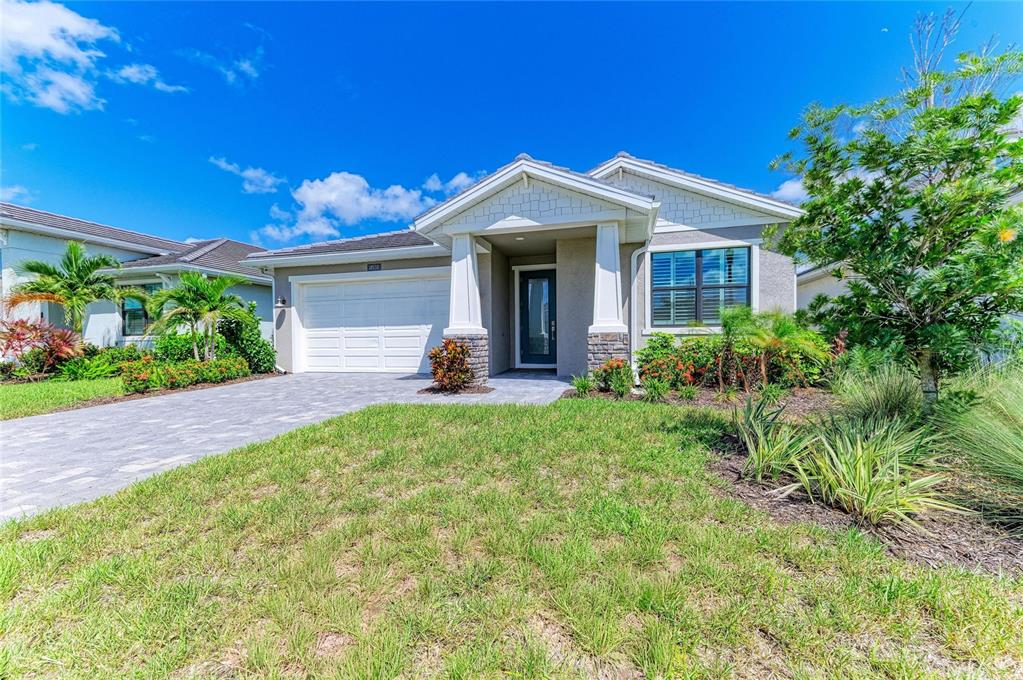 The exterior of a single-story house features a paved driveway, a garage, and a covered entryway — 18530 MIDSUMMER PLACE, VENICE, FL